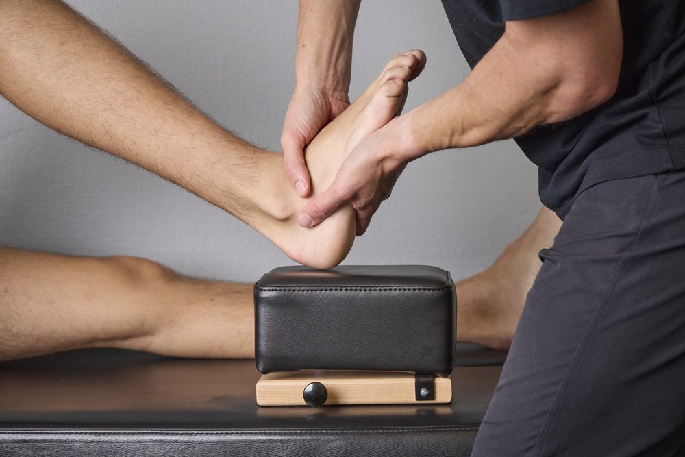 Naprapat behandlar en patients fot och fotled