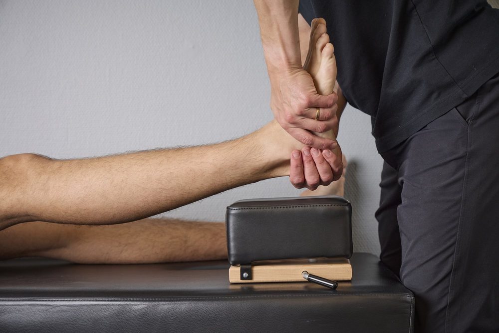 Naprapat undersöker en patients ben och knä